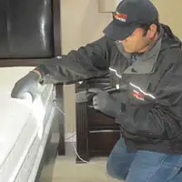 Bed bug inspection technician checking a mattress and bed frame for signs of infestation in Providence, RI