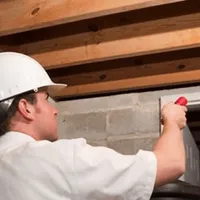 Termite inspection technician checking a basement wall and framing for termite activity in Providence, RI