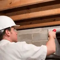 Termite inspection technician checking a basement wall and framing for termite activity in Providence, RI